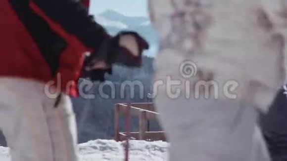 可爱的年轻夫妇站在山上的观景台上一边和滑雪者交谈视频的预览图