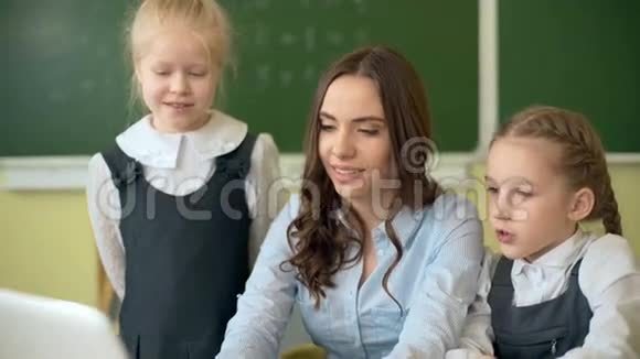 快乐的老师在教室里和学生使用笔记本电脑视频的预览图