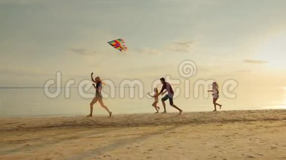 快乐而无忧无虑的童年孩子们玩旧风筝跑过沙滩视频的预览图