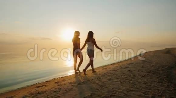 年轻的母亲和她的女儿一个在日落时在海滩上散步的青少年视频的预览图