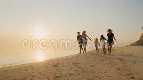 一群不同年龄和成年人无忧无虑的孩子在海滩上跑步很有趣视频的预览图