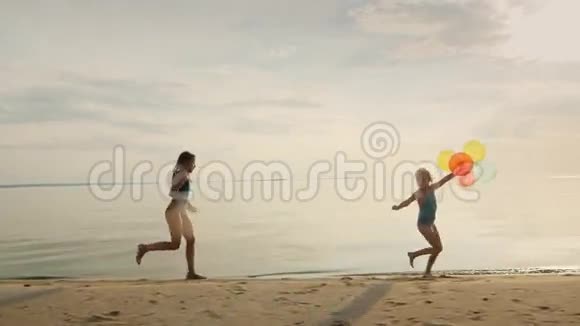 两个姐妹在海滩上一起玩一个女孩跑着跑着手里拿着气球视频的预览图