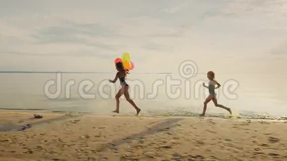 快乐的童年两个姐妹在海滩上互相跑来跑去玩得开心视频的预览图