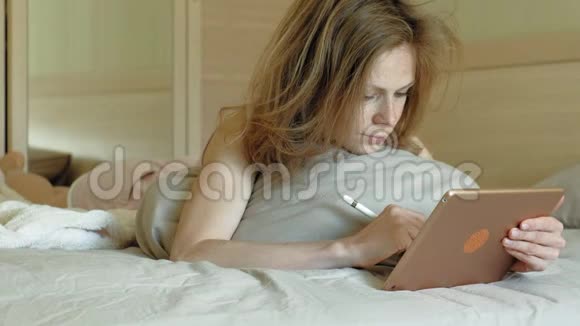 女人在床上用电脑平板电脑上午视频的预览图