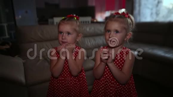 两个穿着漂亮红色连衣裙的迷人双胞胎姐妹正在等待一个点燃蜡烛的蛋糕他们吹蜡烛视频的预览图