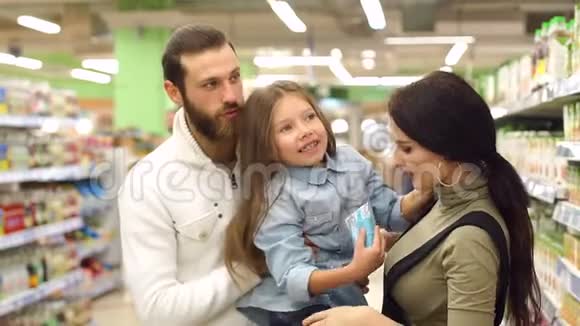 漂亮的父母和他们的女儿正在超市里选择糖果视频的预览图