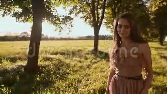 一个留着长发的漂亮女孩走在树间的绿色小径上盘旋着享受着阳光和自然女孩视频的预览图
