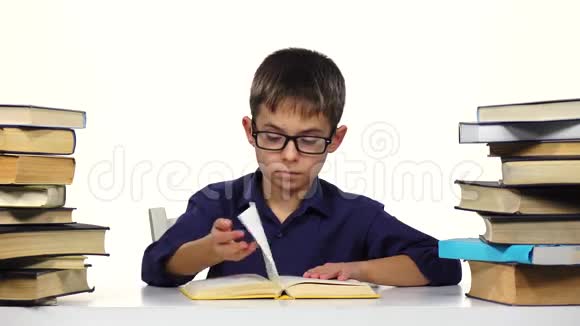 男孩坐在桌子旁翻阅一本书的页数白色背景视频的预览图