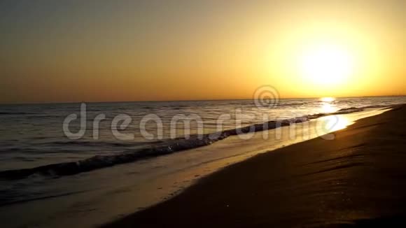 在美丽温暖的傍晚橙色的夕阳西下在沙滩海洋海岸海岸线上缓慢平静令人满意的海浪拍打着视频的预览图