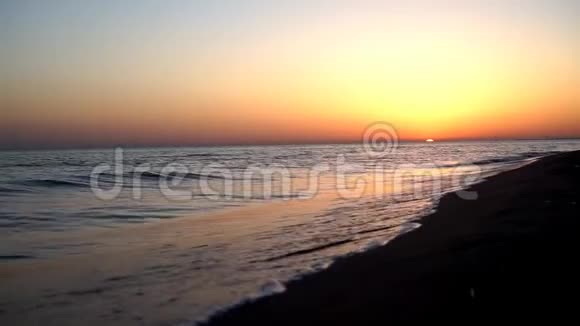 在迷人的温暖的黄昏橙色的日落海景中缓慢平静令人满意的海浪拍打在沙滩海岸海岸线上视频的预览图