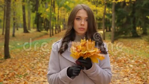 美丽的小姐愁眉苦脸披着枫叶的花束对某人微笑视频的预览图