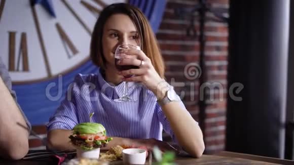 餐馆里的女孩正在喝酒黑发女人给她带来了一个汉堡包她准备吃了非常好视频的预览图