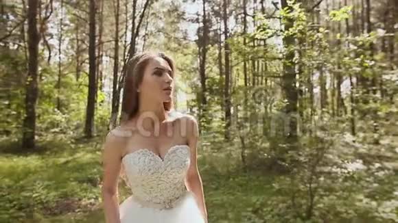 华丽时尚的新娘穿着复古的白色连衣裙走在森林里视频的预览图