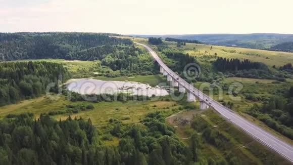 在乡间道路上驾驶汽车穿过森林的鸟瞰图一杯驶过森林道路的汽车视频的预览图