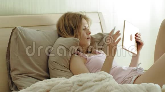 女人在床上用电脑平板电脑上午视频的预览图