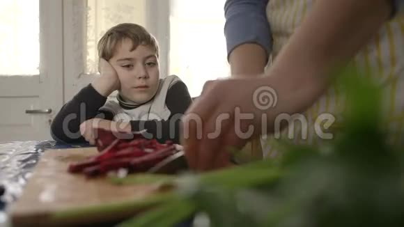 儿子看着妈妈为午餐切红甜菜视频的预览图