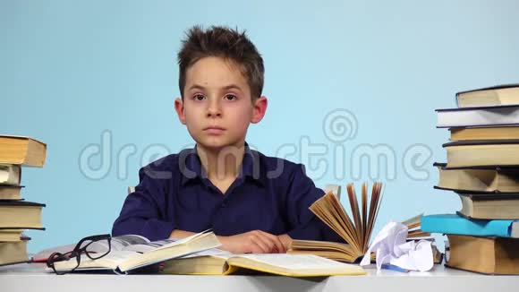 疲惫的男孩开始合上书把书折起来蓝色背景视频的预览图