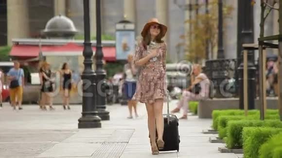 带着门票和手提箱在市中心微笑的女孩游客她在行走在召唤生命视频的预览图
