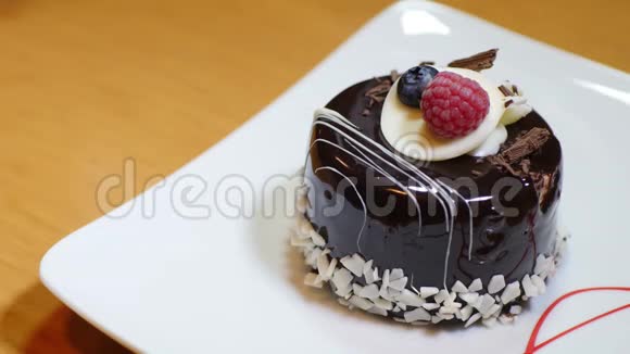 一个装饰好的单份蛋糕躺在白色盘子里一个人开始用叉子吃它视频的预览图