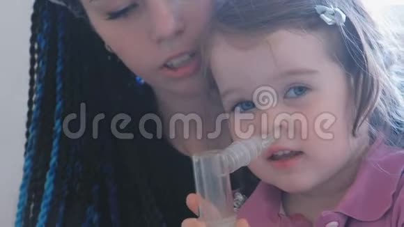 小可爱的女孩和她妈妈一起通过吸入面罩吸入使用雾化器和吸入器进行治疗视频的预览图