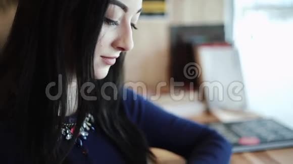 美丽的黑发女人坐在咖啡馆里喝着卡布奇诺看着纸上印的照片视频的预览图