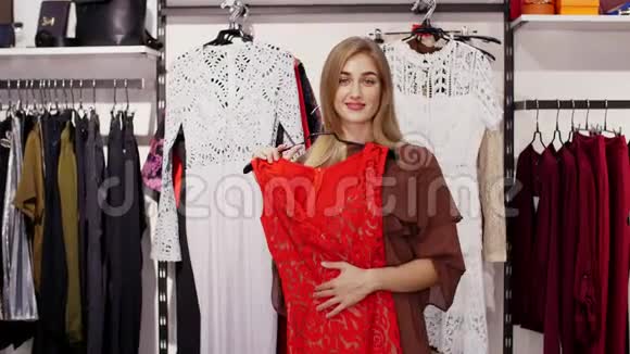 女孩高个子漂亮的金发女人在商店里挑选衣服在镜子前欣赏自己微笑着视频的预览图