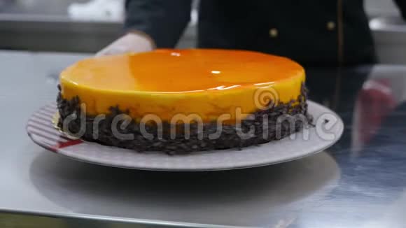 一个糖果师在旋转蛋糕架上旋转一个橙色蛋糕视频的预览图