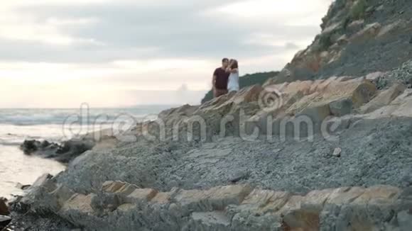 夏天晚上年轻的男人和女人站在海滩上接吻视频的预览图