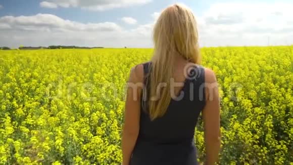 年轻的金发女人在美丽的油菜田里奔跑视频的预览图