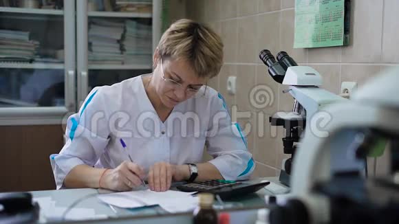 其办公室医生填写处方或病史一位戴着眼镜纸的中年妇女视频的预览图