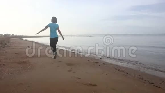 女孩在日出时沿着海滩慢跑视频的预览图