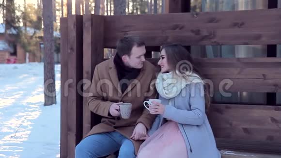 爱的夫妻在冬天的小屋后院喝热茶视频的预览图