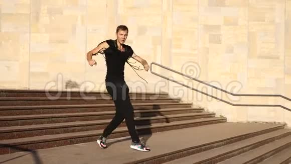 一个年轻快乐的家伙跳着现代芭蕾舞在街上的楼梯上摇摇晃晃的慢分子视频的预览图