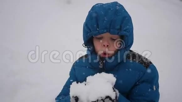 男孩用双手特写的方式吹雪暴风雪视频的预览图