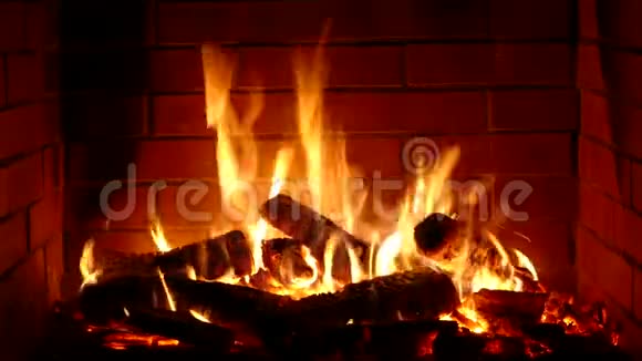 在舒适的砖制壁炉氛围中用橙色火焰缓慢燃烧的木头上拍摄的非常令人满意的特写镜头视频的预览图