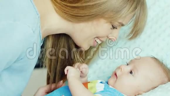 幸福的年轻母亲微笑着对他的儿子两个月婴儿躺在婴儿床上视频的预览图