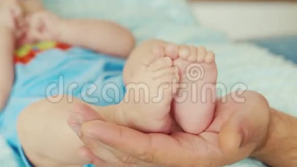 一只成年雄性手握着一只小婴儿的脚视频的预览图