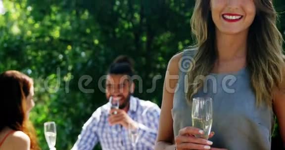 女人站在香槟杯边朋友在后台互动的肖像视频的预览图