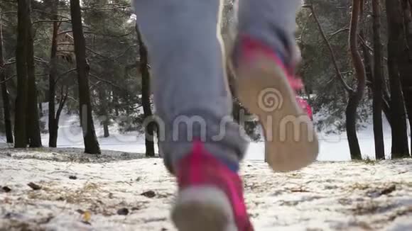 在寒冷的冬季森林里慢跑的女跑步者穿着温暖的运动服装和手套视频的预览图