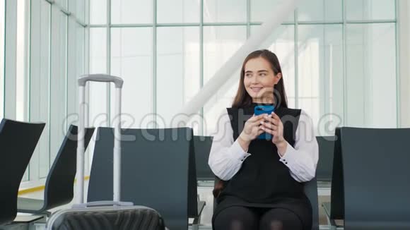 戴着笔记本电脑手机和行李坐在机场微笑的亚洲女商人的侧面肖像终点站铁路视频的预览图