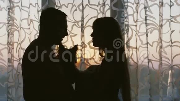 一对幸福可爱的夫妇站在窗户附近接吻妈妈握着婴儿的手视频的预览图