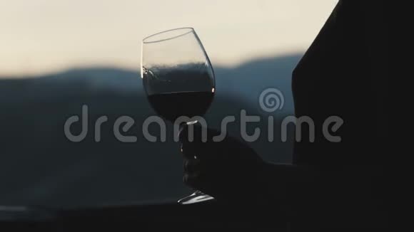 年轻女子喝着酒杯里的红酒看着夕阳视频的预览图