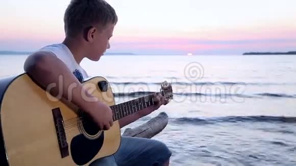 男孩在日落时弹吉他视频的预览图