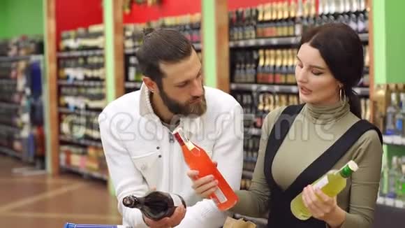 年轻的一对微笑的夫妇在超市选择香槟和白酒视频的预览图