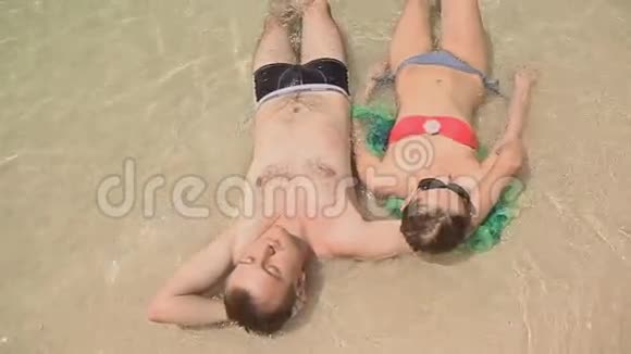 一对年轻夫妇躺在沙滩上视频的预览图