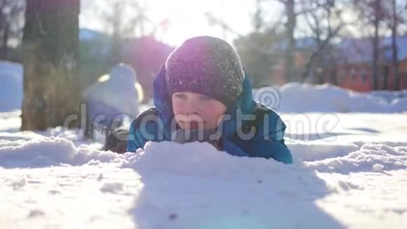 快乐的孩子在阳光明媚的一天在冬季公园玩得很开心躺在雪地里视频的预览图