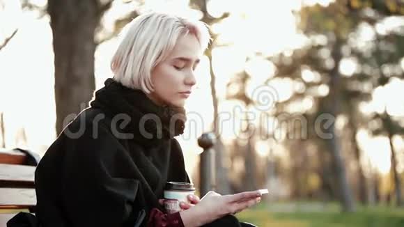 金发女郎端着咖啡看着智能手机突然转了个身相机惊喜的脸叫视频的预览图