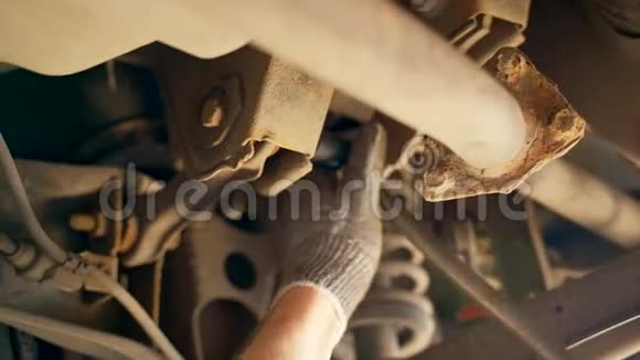检查坑内一名汽车技工用扳手拧开汽车上的螺栓弯曲和脚趾的调整视频的预览图
