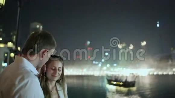 情侣在夜城喷泉的背景下互相欣赏视频的预览图