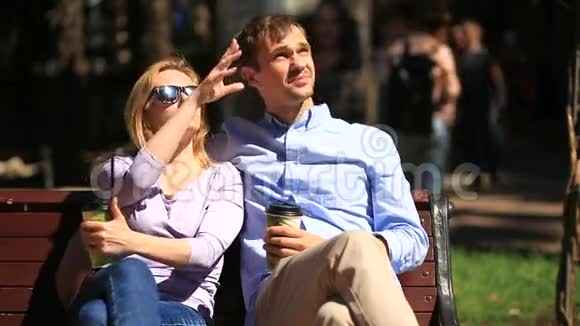 男人和女人坐在长凳上一个男人和一个漂亮的女人约会他们喝咖啡聊天视频的预览图